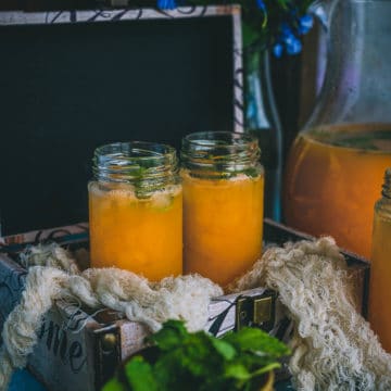 2 glasses filled with Organic Energy Drink With Carrots, Orange and Cantaloupe placed in a box