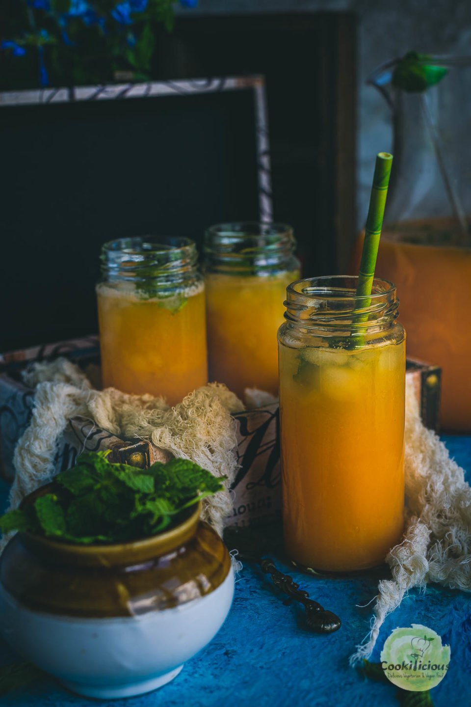 one glass filled with Organic Energy Drink With Carrots, Orange and Cantaloupe with a straw in it and two glasses filled with the same in the background