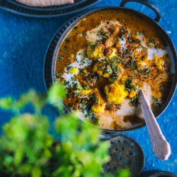 Cauliflower Tikka Masala - Easy Vegan Curry served in a small kadai with a spoon in it