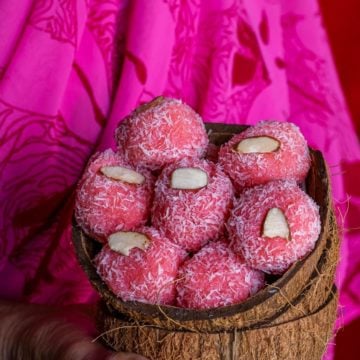 a lady holding coconut shells filled with Instant Rose flavored Coconut Ladoo
