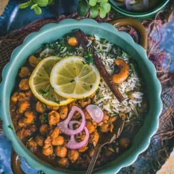 a round bowl filled with Vegan Chana Masala with a spoon in it