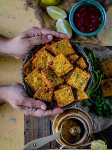 a set of hands holding a platter full of fried Vegan Cabbage Fritters