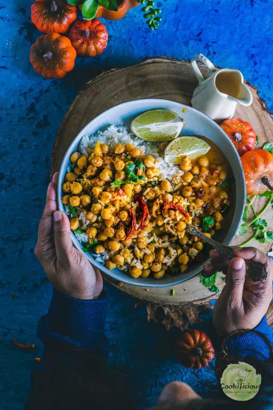 one hand holding the bowl while the other hand is holding a spoon and digging into the bowl filled with Instant Pot Butternut Squash Chickpea vegan Thai Curry