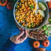 a hand holding a spoon and digging into a bowl of Instant Pot Butternut Squash Chickpea vegan Thai Curry