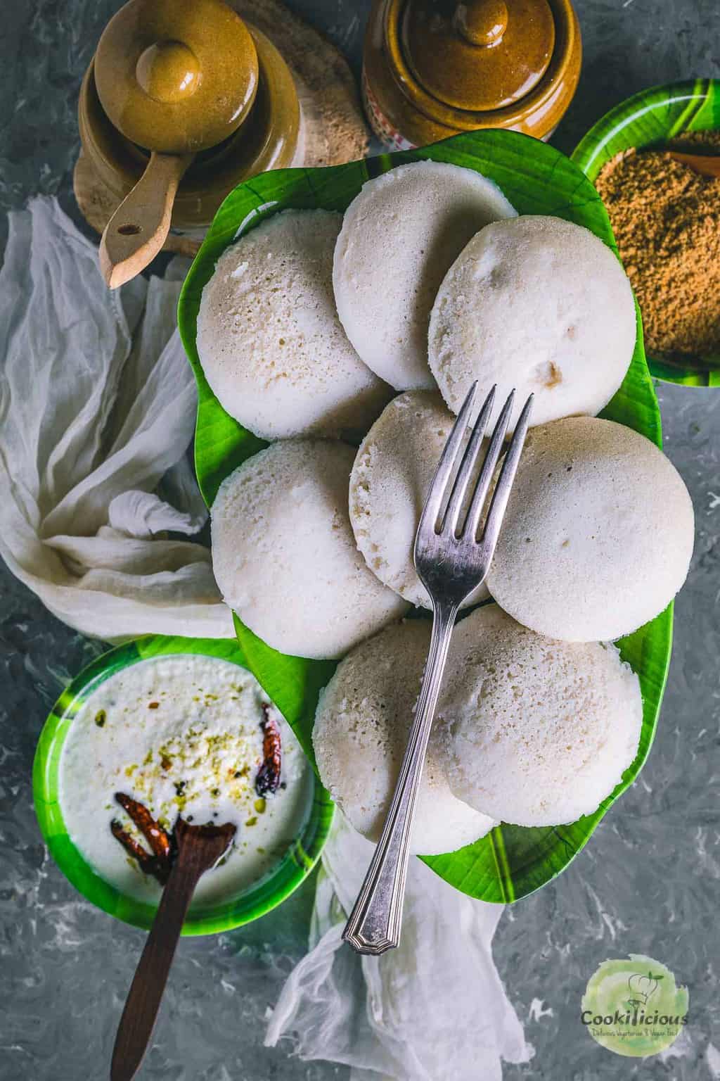 a plate full of idlis with one fork on top