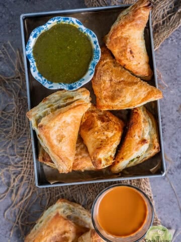 Party-ready vegan samosa puffs on a festive holiday table with chai and chutney.
