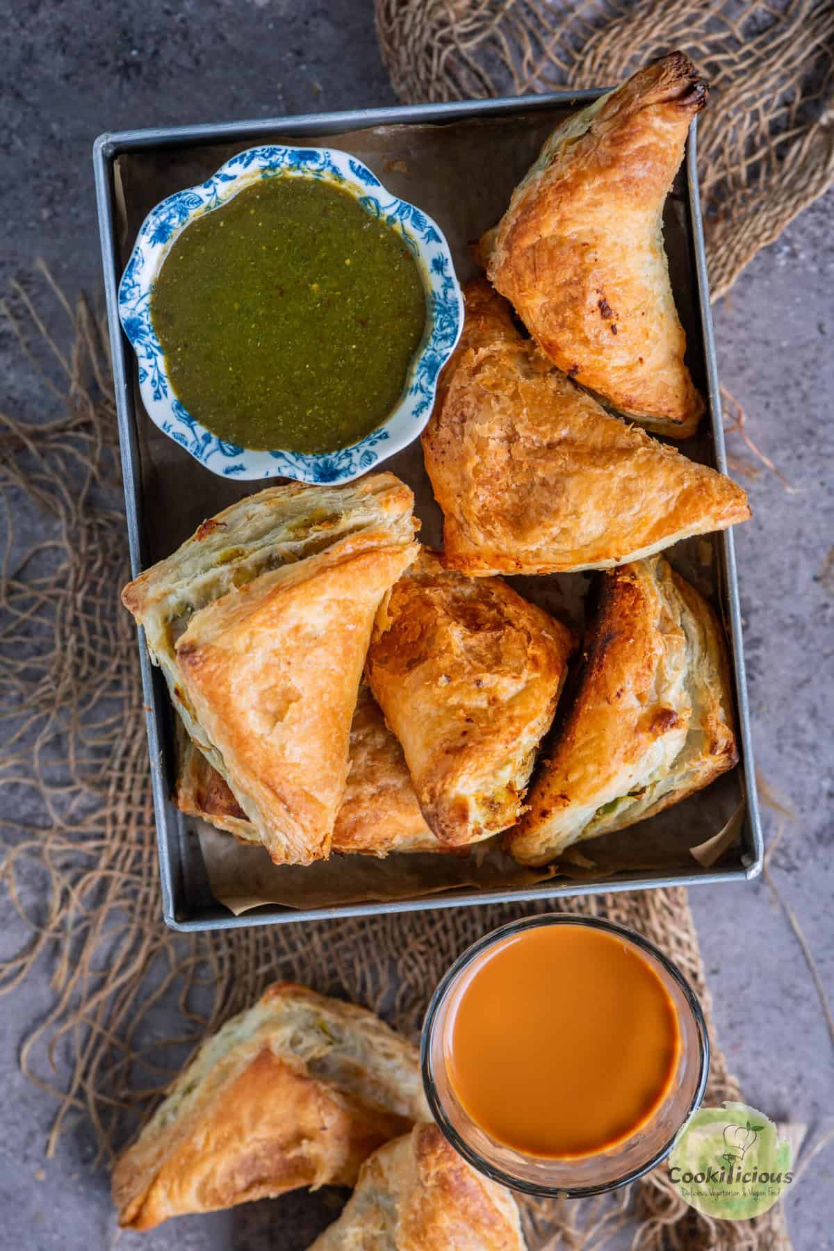 Party-ready vegan samosa puffs on a festive holiday table with chai and chutney.