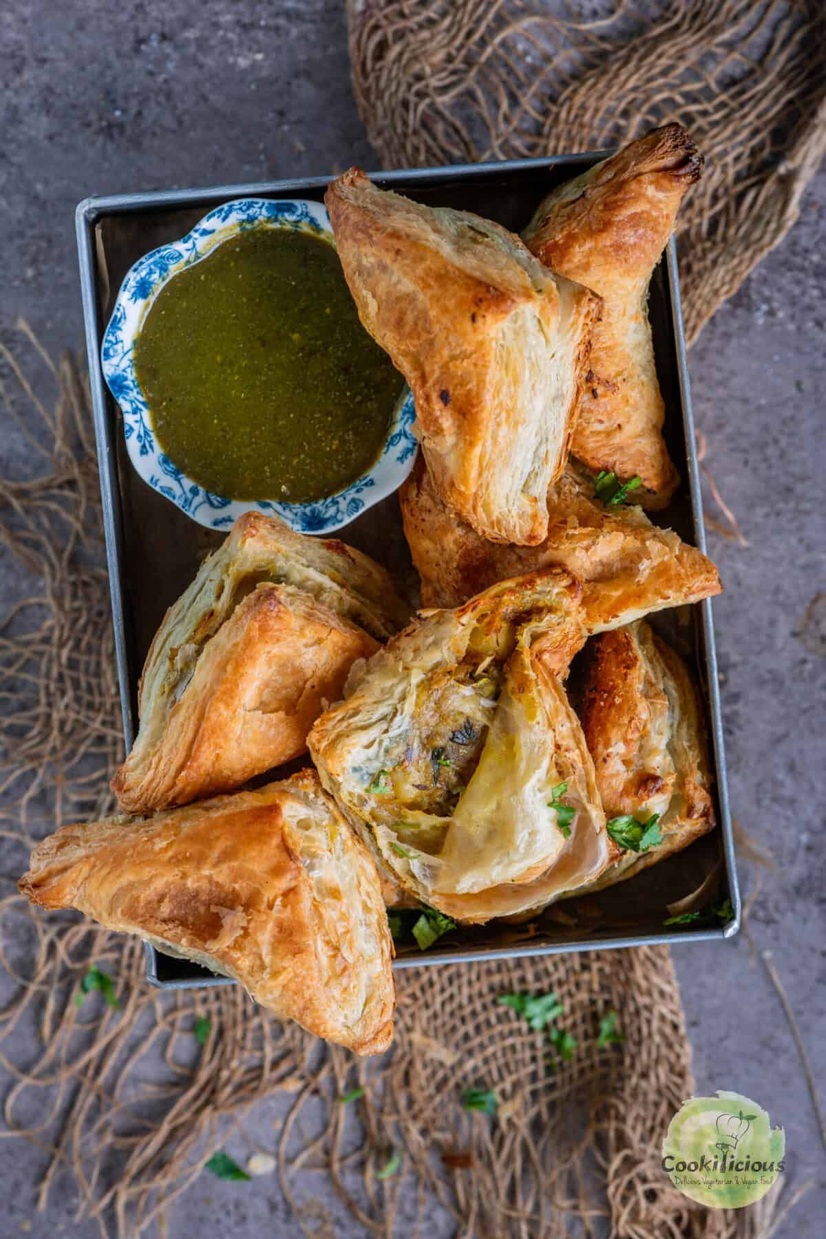 Close-up of golden baked vegan samosa puff pastry filled with spiced potato masala.