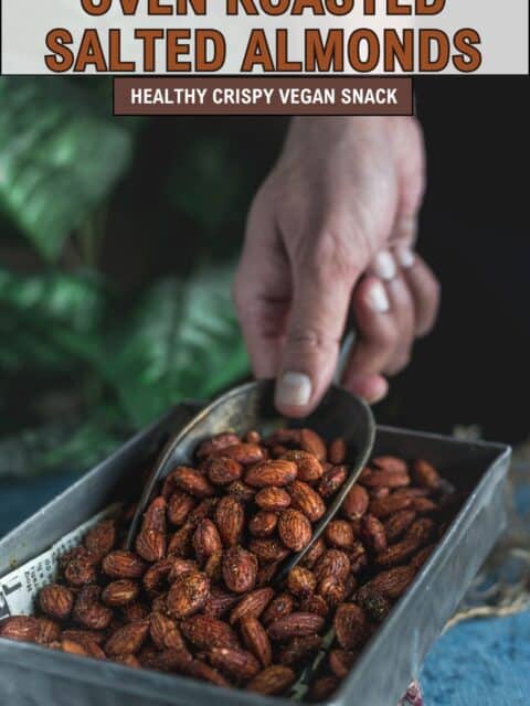 a hand scooping out roasted salted almonds from a tray and text at the top and bottom.