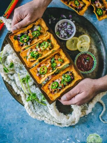 a set of hands serving a platter filled with Instant Pot Black Beans Taco Boats