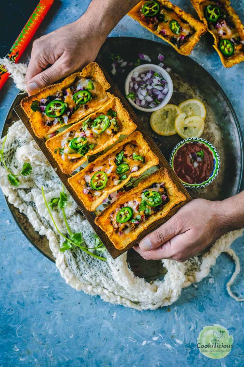 a set of hands serving a platter filled with Instant Pot Black Beans Taco Boats