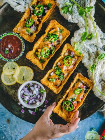 one hand reaching out to pick one of the Instant Pot Black Beans Taco Boats