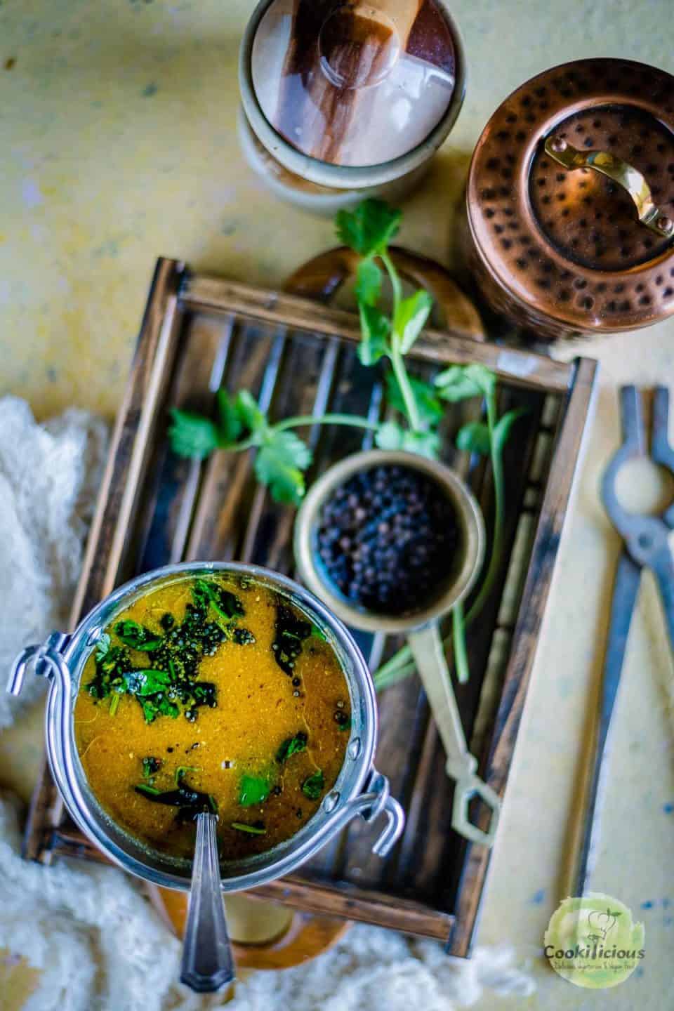Jeera Milagu Rasam served in a bucket and placed on a wooden tray