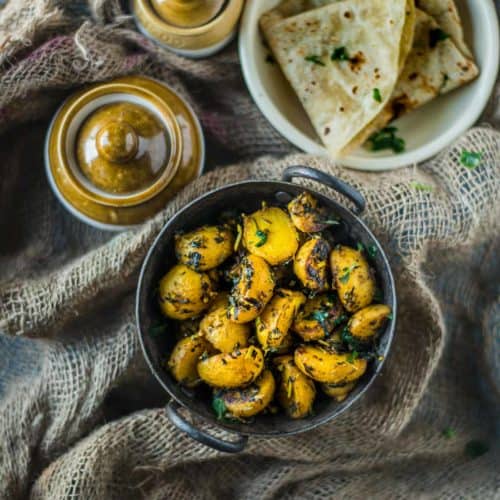 Aloo Methi served with chapati and pickle jars on the side