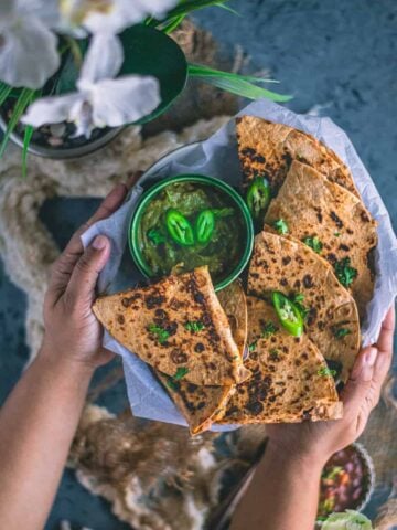 a set of hands holding a platter filled with Tandoori Cheese Quesadilla
