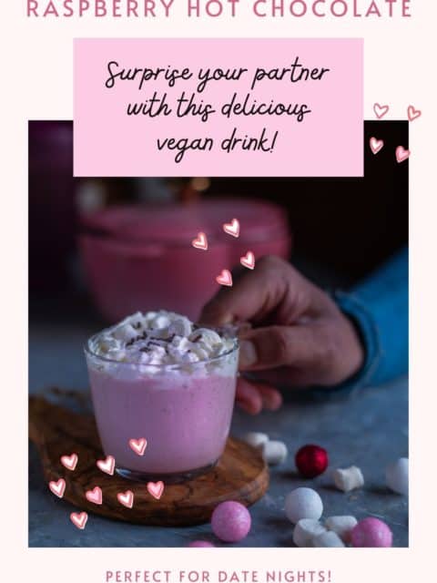 one hand picking up a glass mug filled with Vegan Raspberry Rose Hot Chocolate and text at the top and bottom