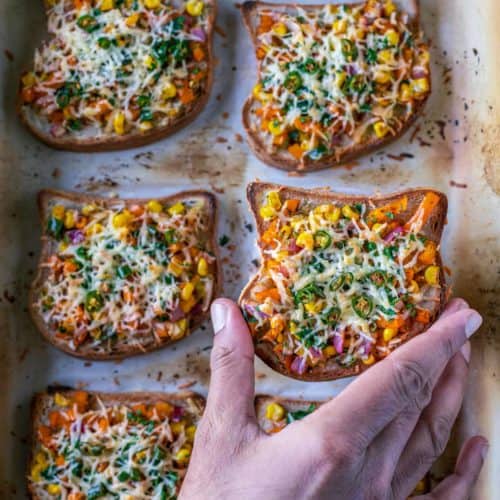 one hand picking up one Vegan Chilli Cheese Corn Toast from the baking tray