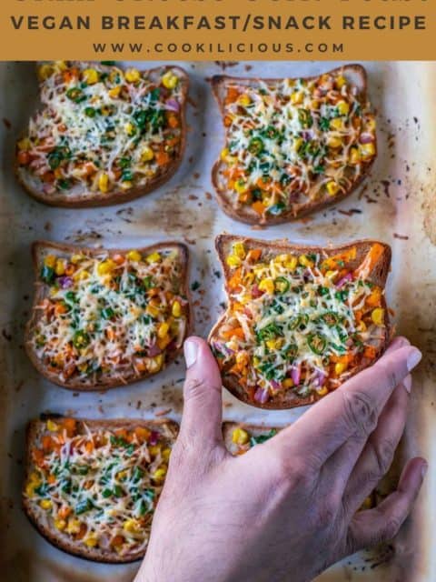 one hand picking up one Vegan Chilli Cheese Corn Toast from the baking tray and text at the top
