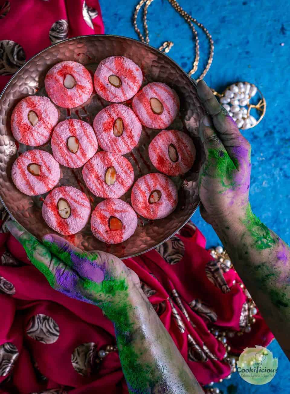 a set of colored hands holding a plate full of Rose Sandesh - Bengali Sweet Recipe