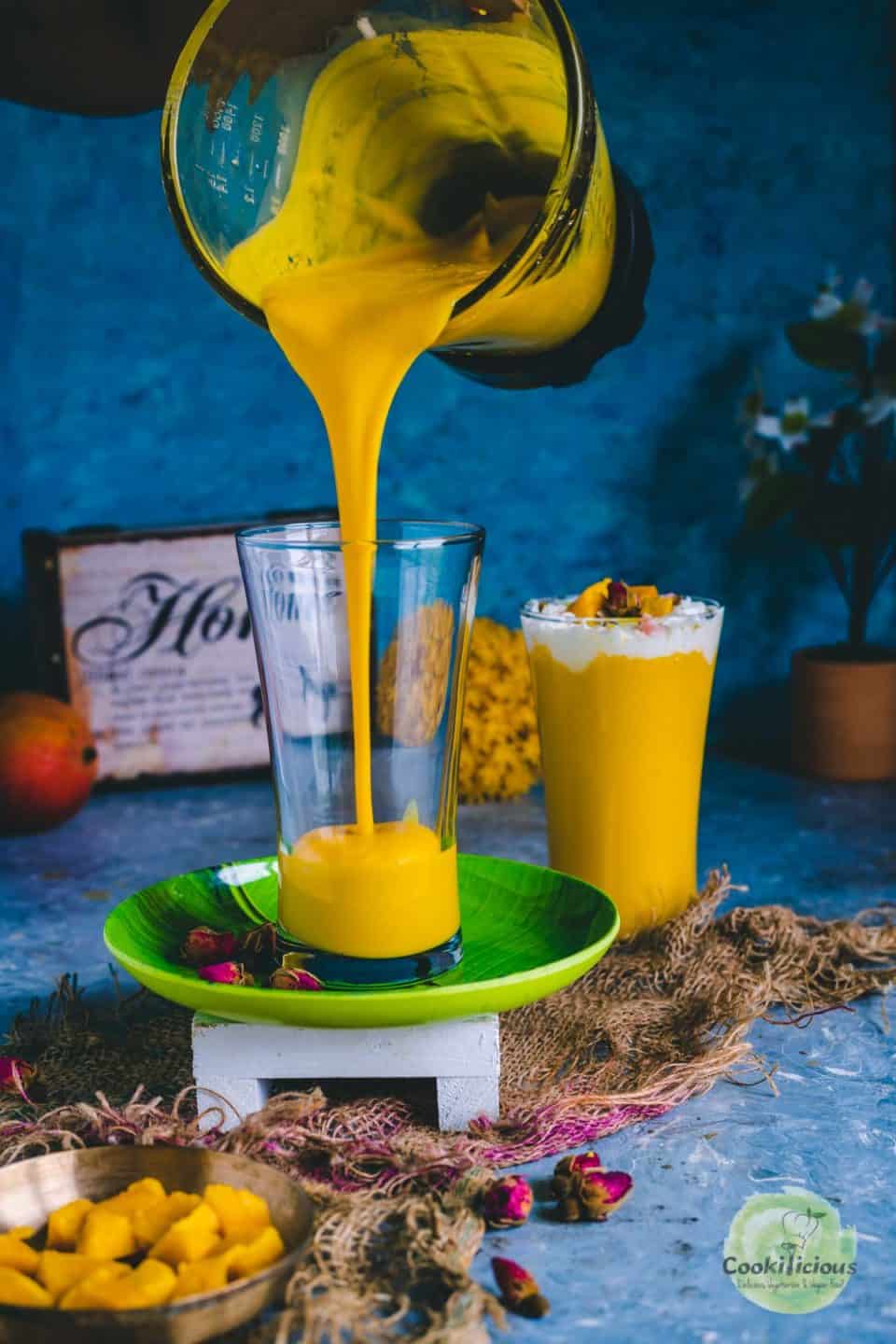 Mango milkshake being poured into a glass from a blender jar