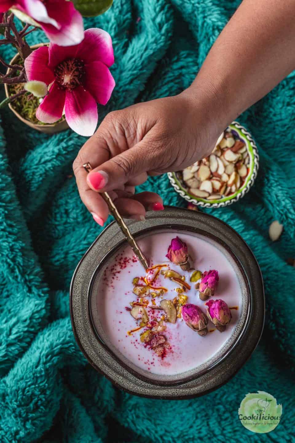 one hand digging into a bowl of Vegan Rose Basundi  with a spoon