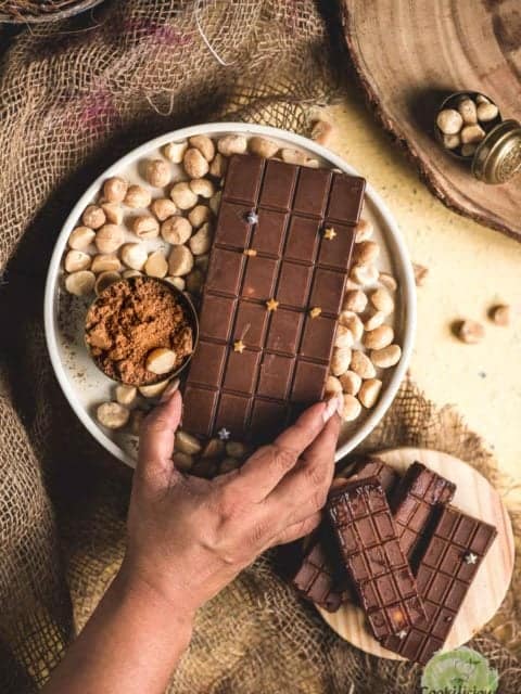 a hand reaching out to grab a Vegan Chocolate Macadamia Bar