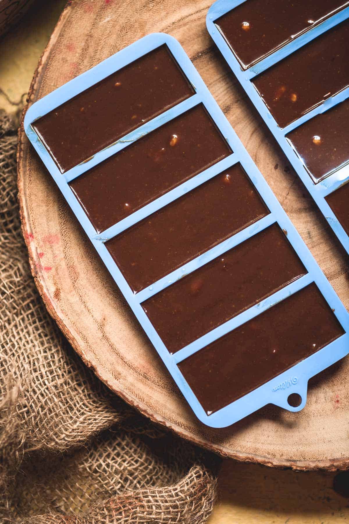Vegan chocolate batter poured into chocolate bar molds before freezing.