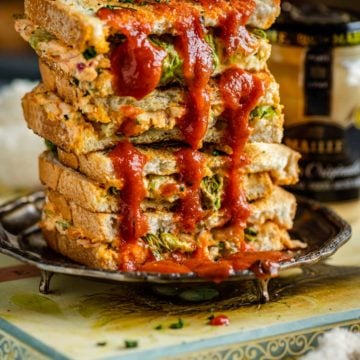 a stack of Veggie Sandwiches with red sauce over it