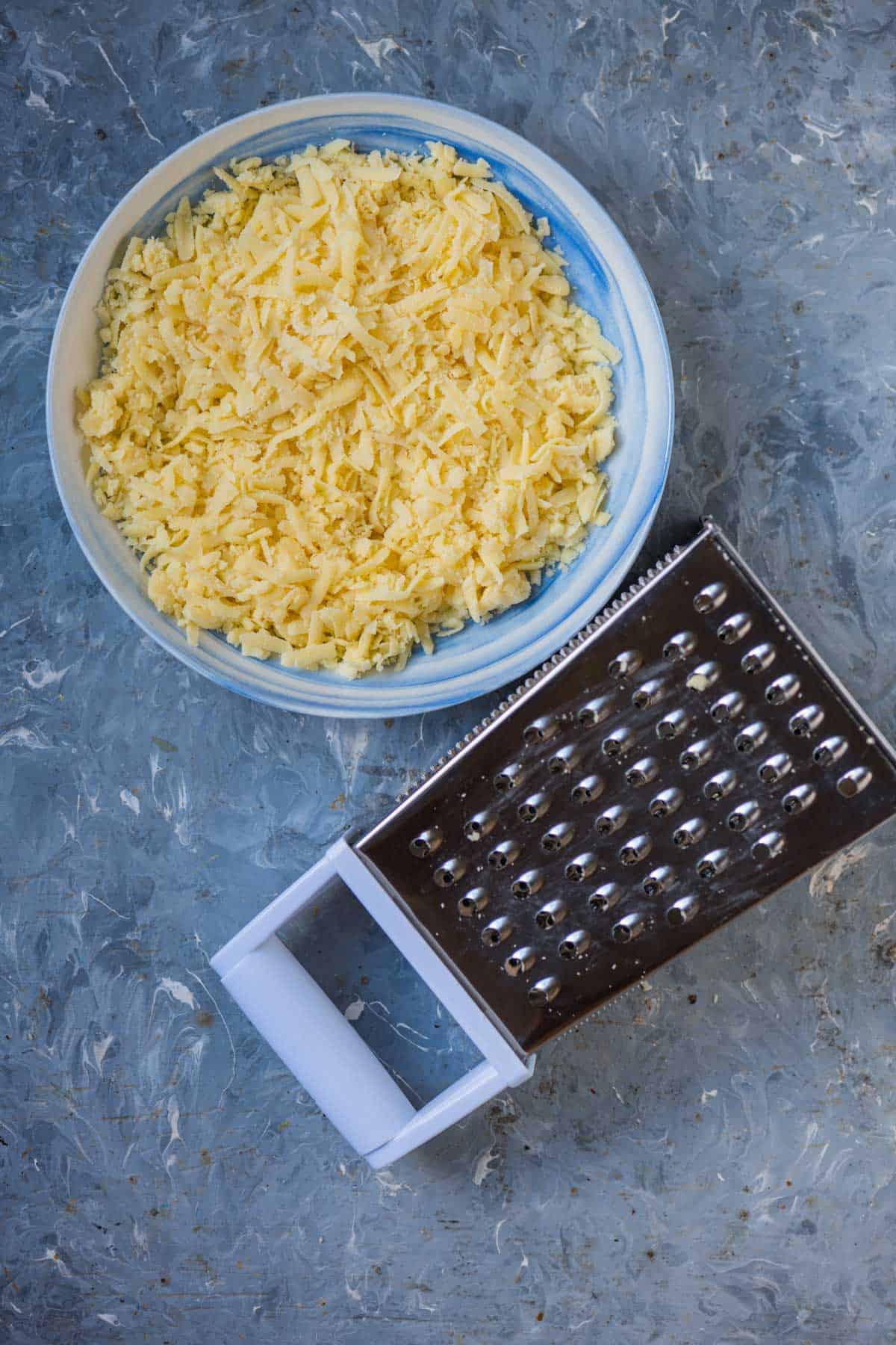 Grating khoya or mawa into shreds by a hand grater.
