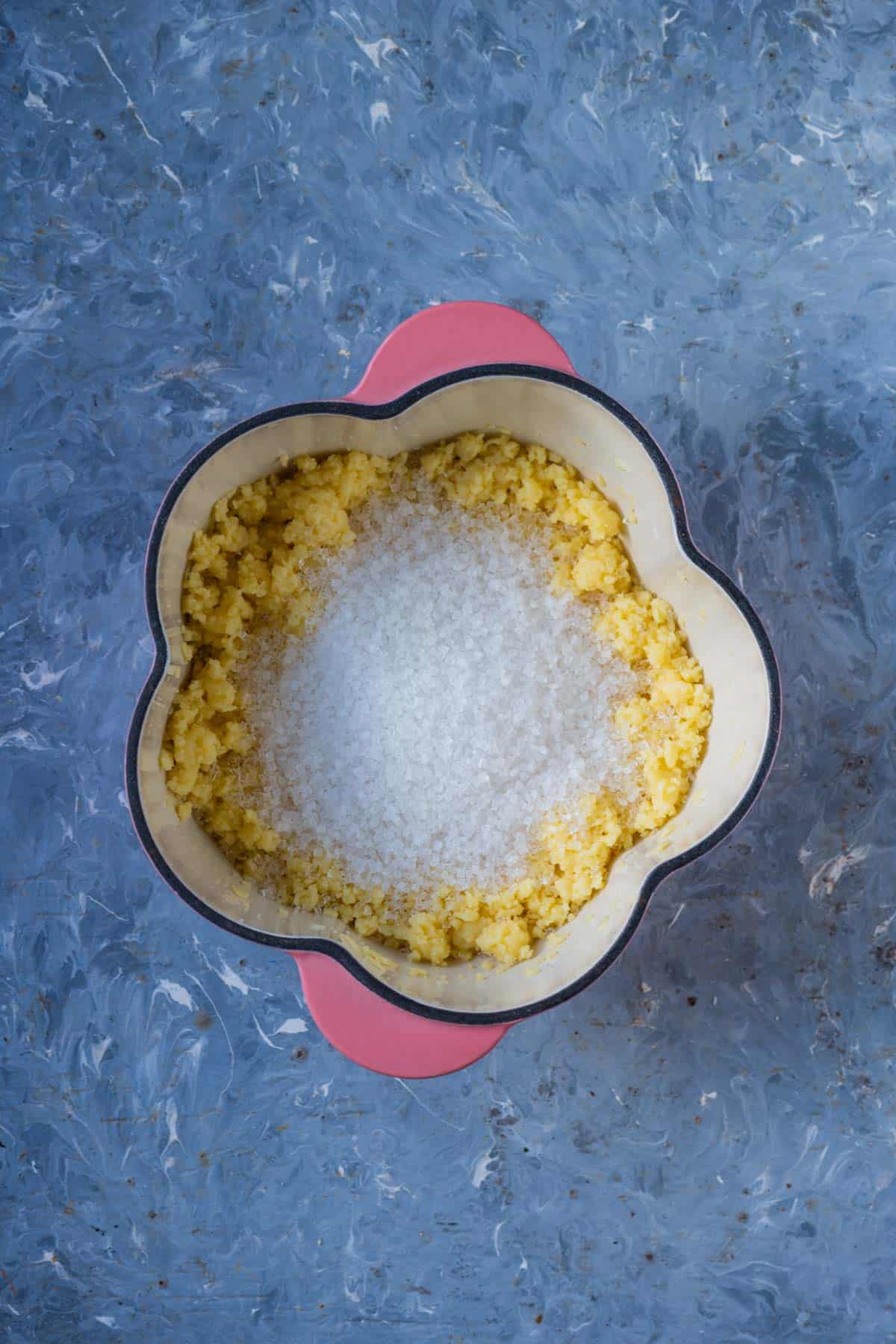 Sugar being stirred into melted khoya in a pan.
