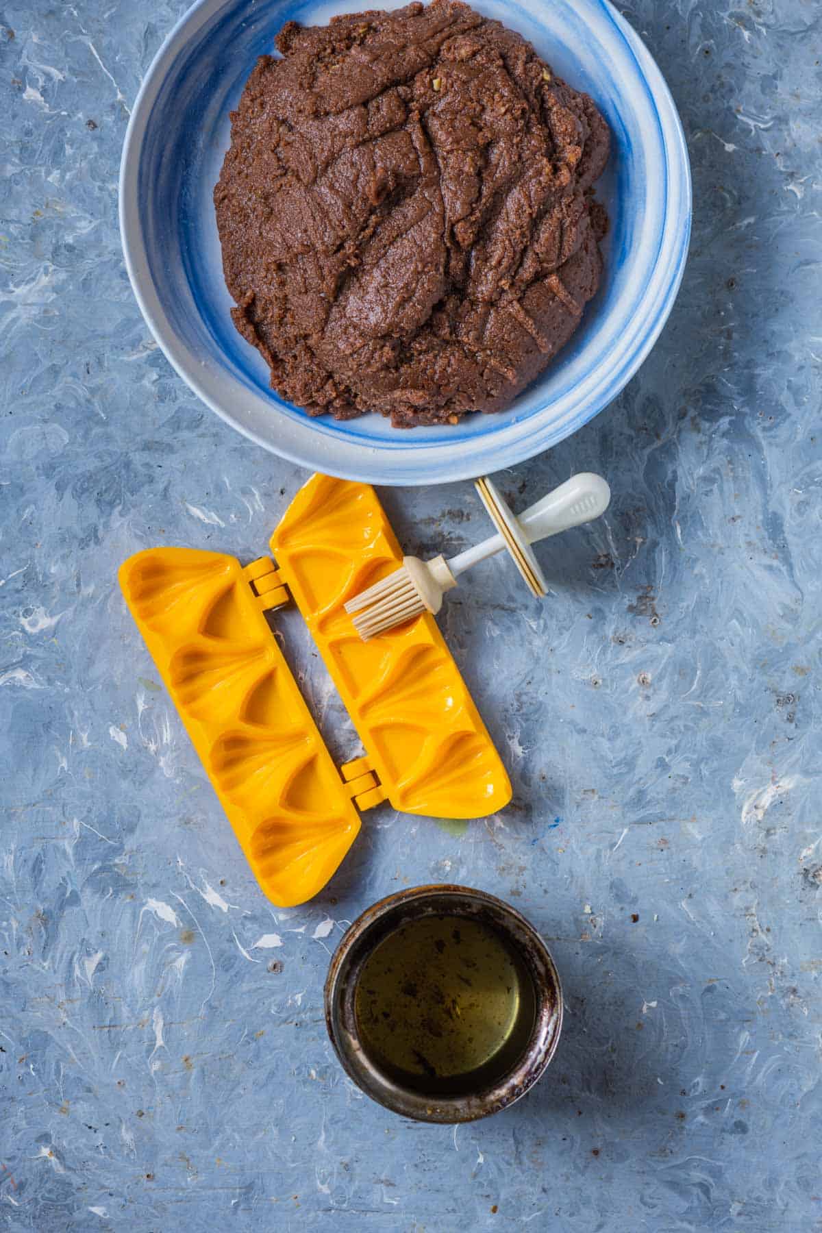 Cooled chocolate mawa mixture on a greased plate next to a modak mold.