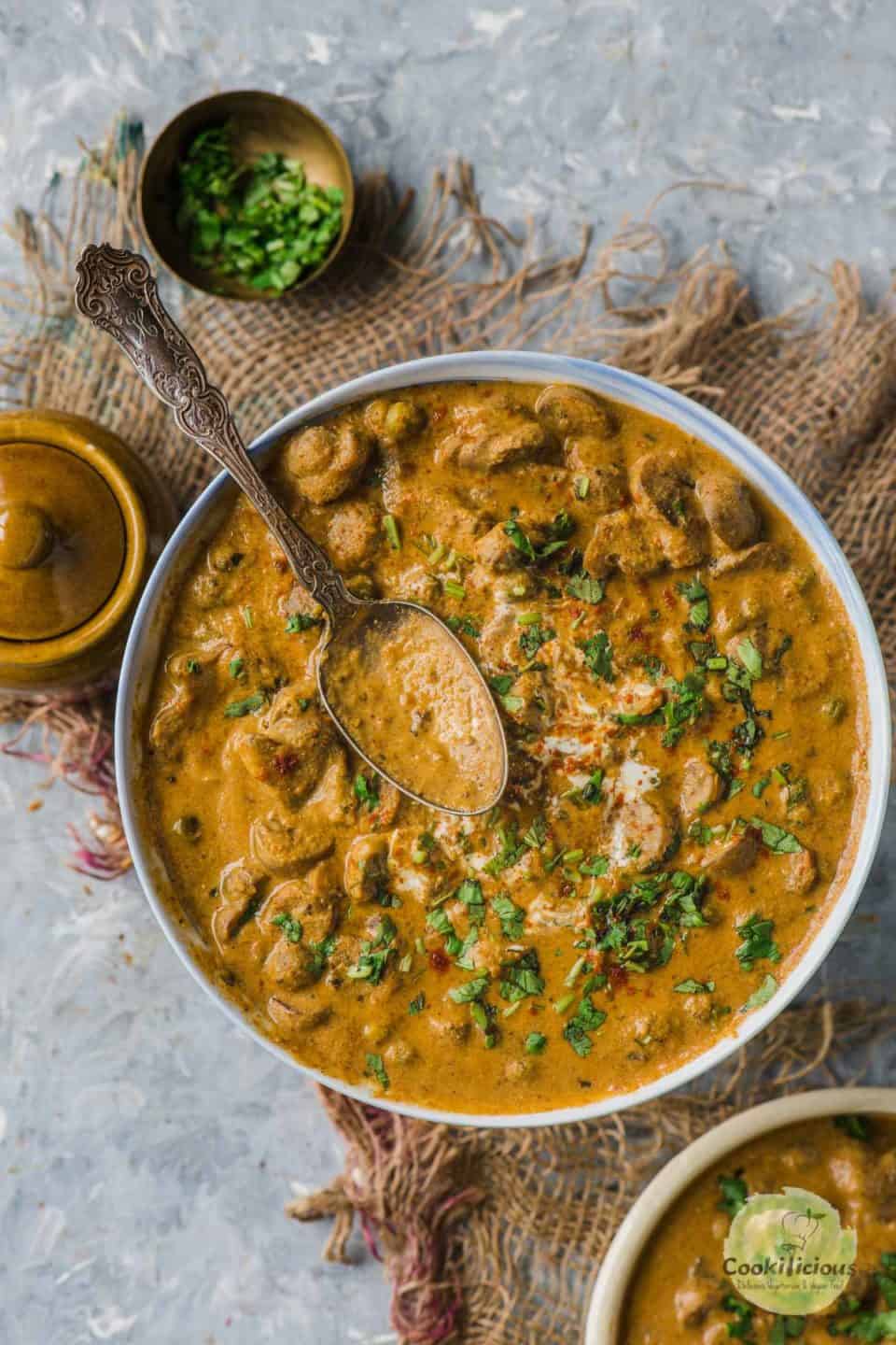 a bowl of Mushroom Masala with a spoon resting on top