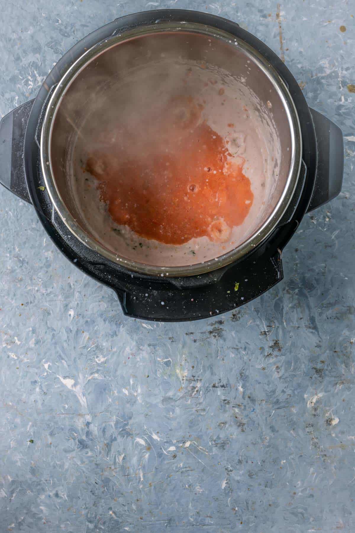 Stirring tomato and chili puree into the curry base.