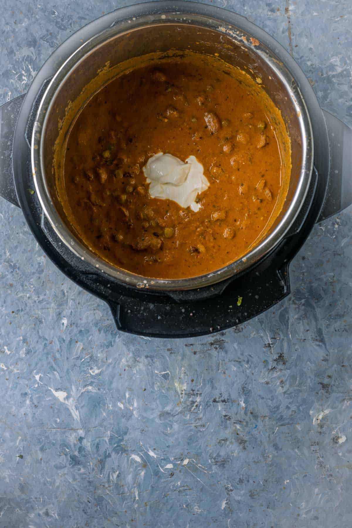Stirring vegan sour cream into mushroom masala for creamy texture.