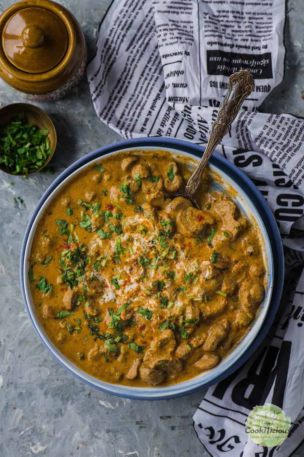 Instant Pot Mushroom Masala served in a bowl with a spoon in it.