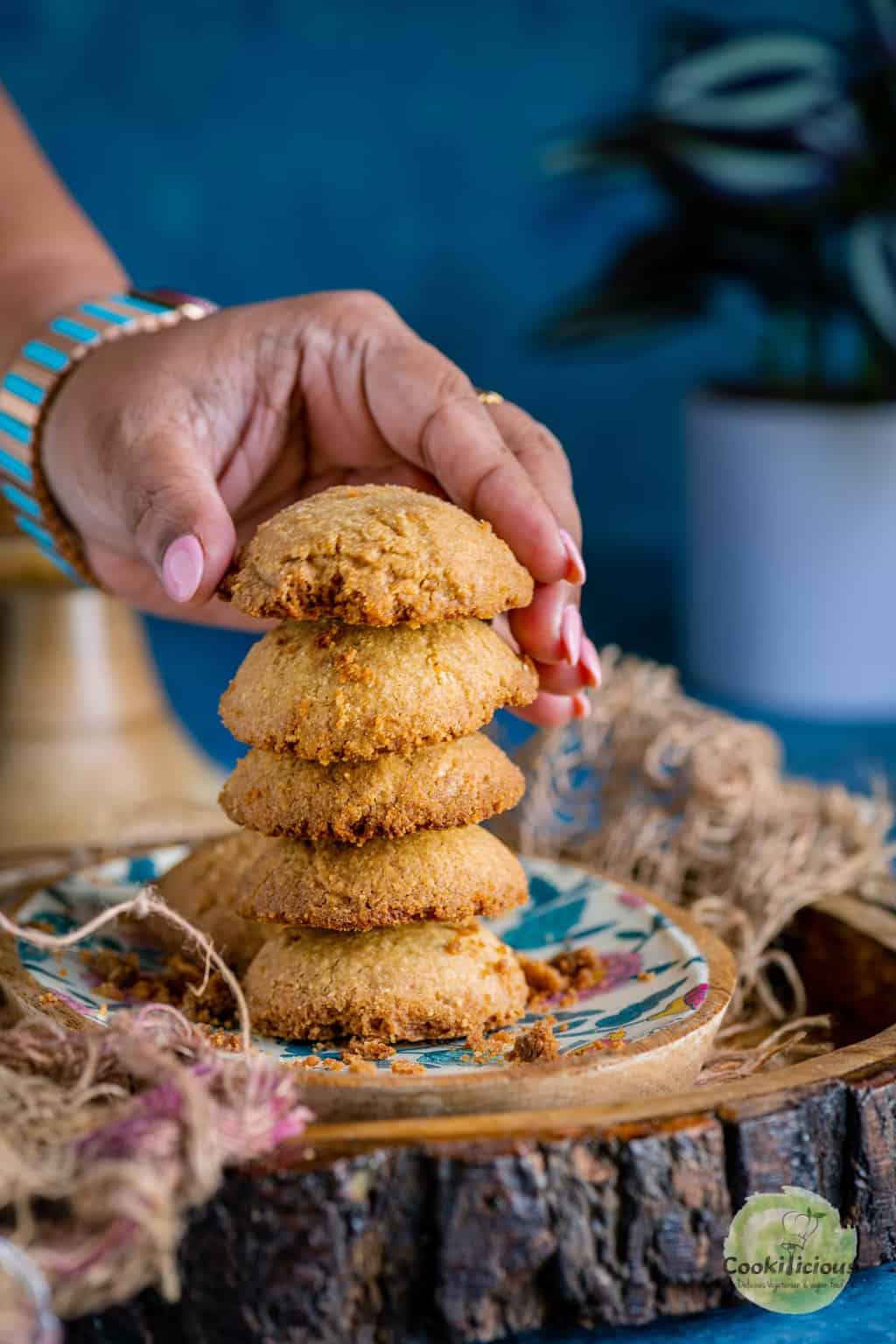 a hand picking up one Whole Wheat Ghee Cookie from a stack