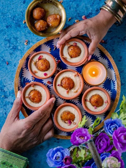 2 hands reaching out to pick a Gulab Jamun Malai matka Kulfi