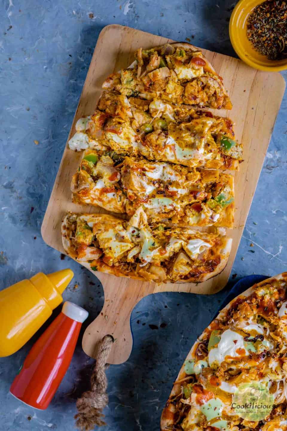 Paneer Naan Pizza cut in slices and served on a wooden board