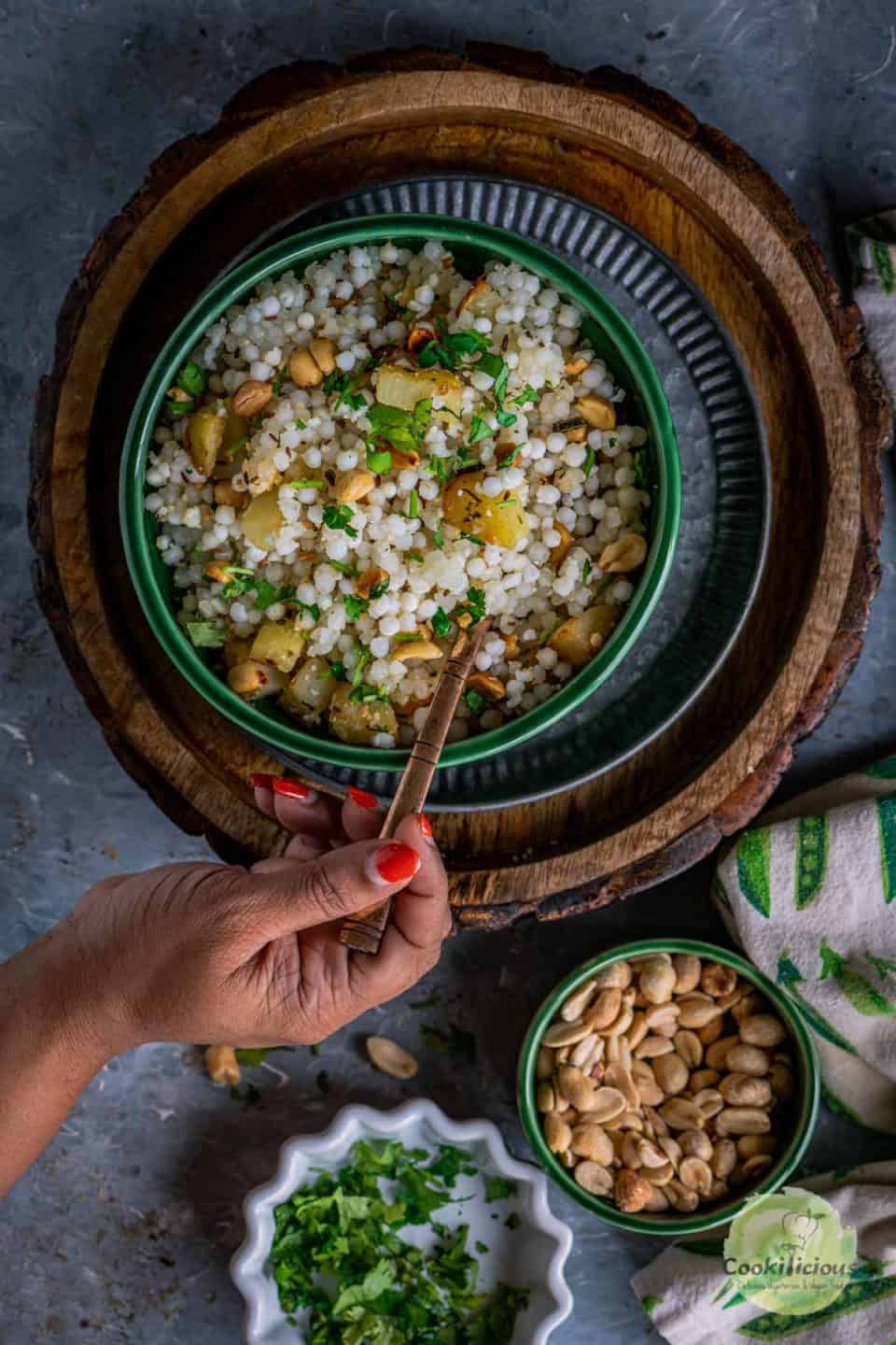 a hand digging into a bowl of Sabudana Khichdi with a spoon
