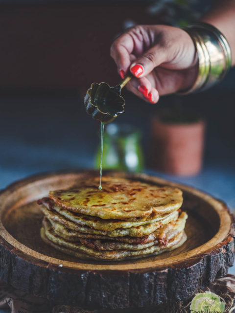 a hand pouring ghee over sweet potato puran poli