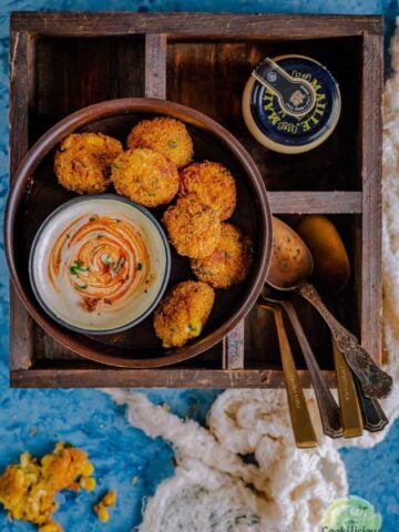 Cheese Corn Balls/Croquettes served in a round platter with spoons on the side