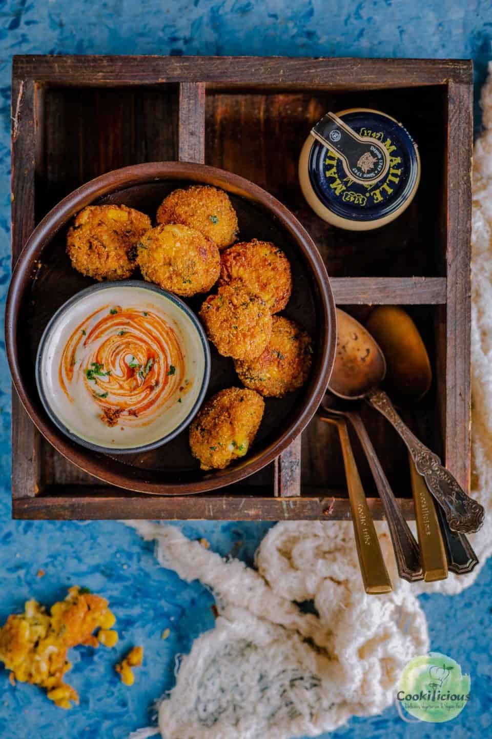Cheese Corn Balls/Croquettes served in a round platter with spoons on the side