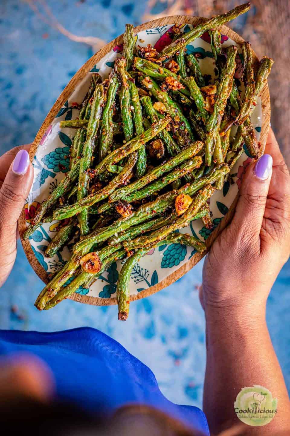 a set of hands carrying a plate of Air Fried Green Beans