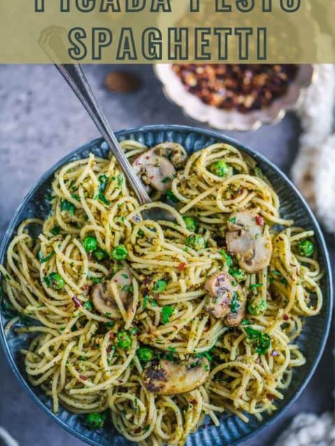 Almond Picada Pesto Spaghetti served in a plate with a fork in it and text at the top