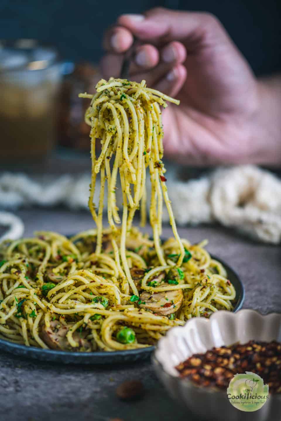 a hand lifting Almond Picada Pesto Spaghetti with a fork