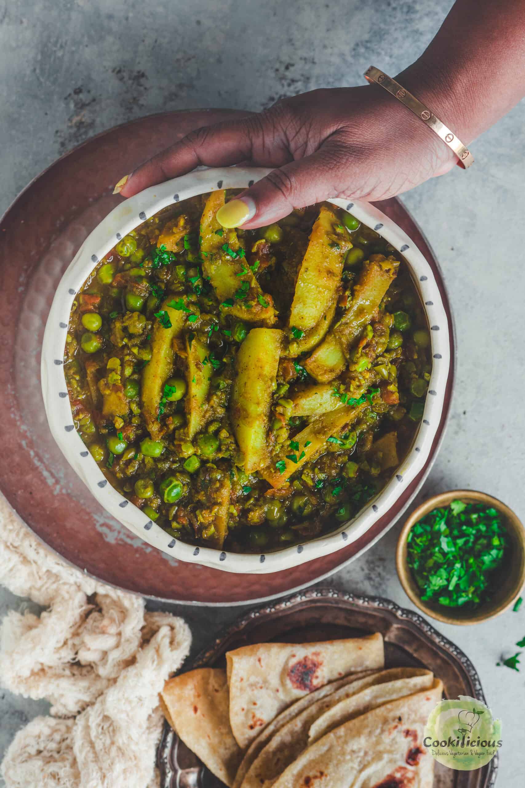 a hand holding a bowl of Matar ka Nimona.