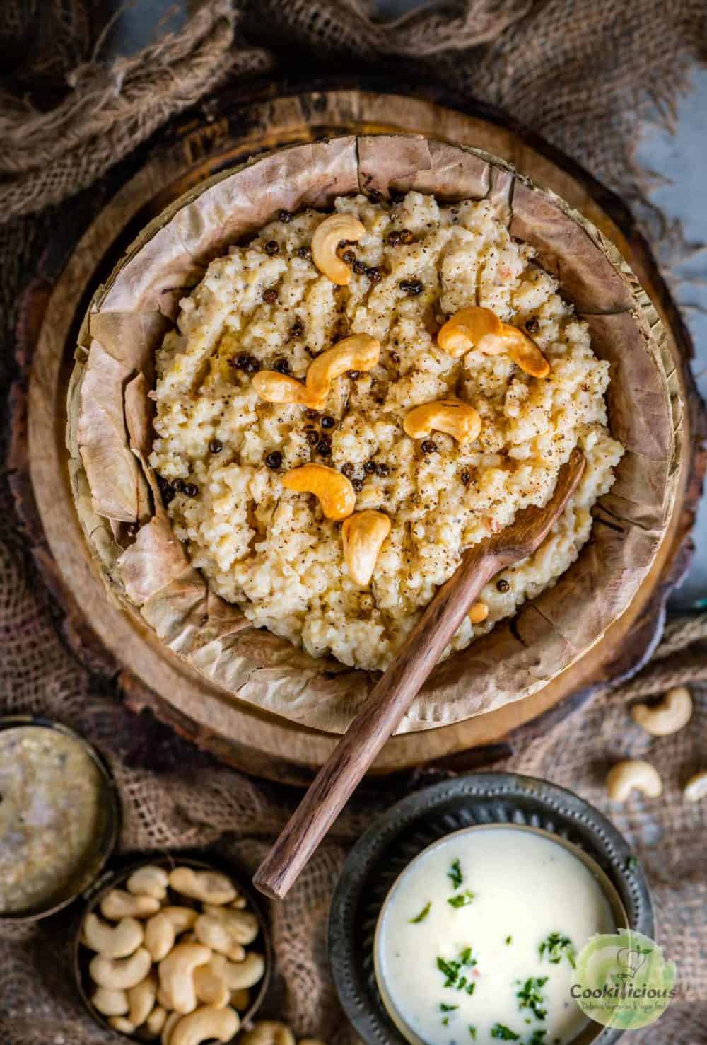 Instant Pot Ven Pongal served in a leaf bowl with a wooden spoon in it