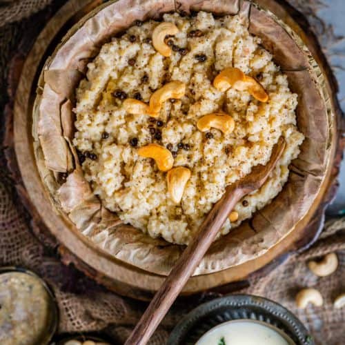 Instant Pot Ven Pongal served in a leaf bowl with a wooden spoon in it