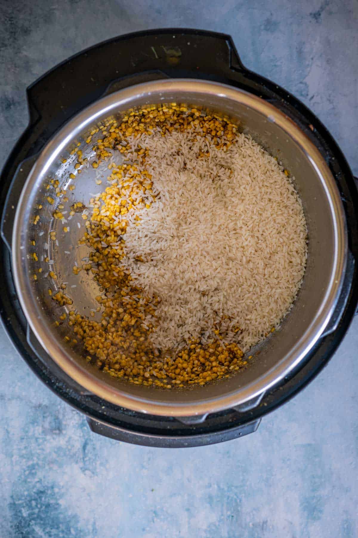 Rice and moong dal mixed with spices in the Instant Pot before pressure cooking.
