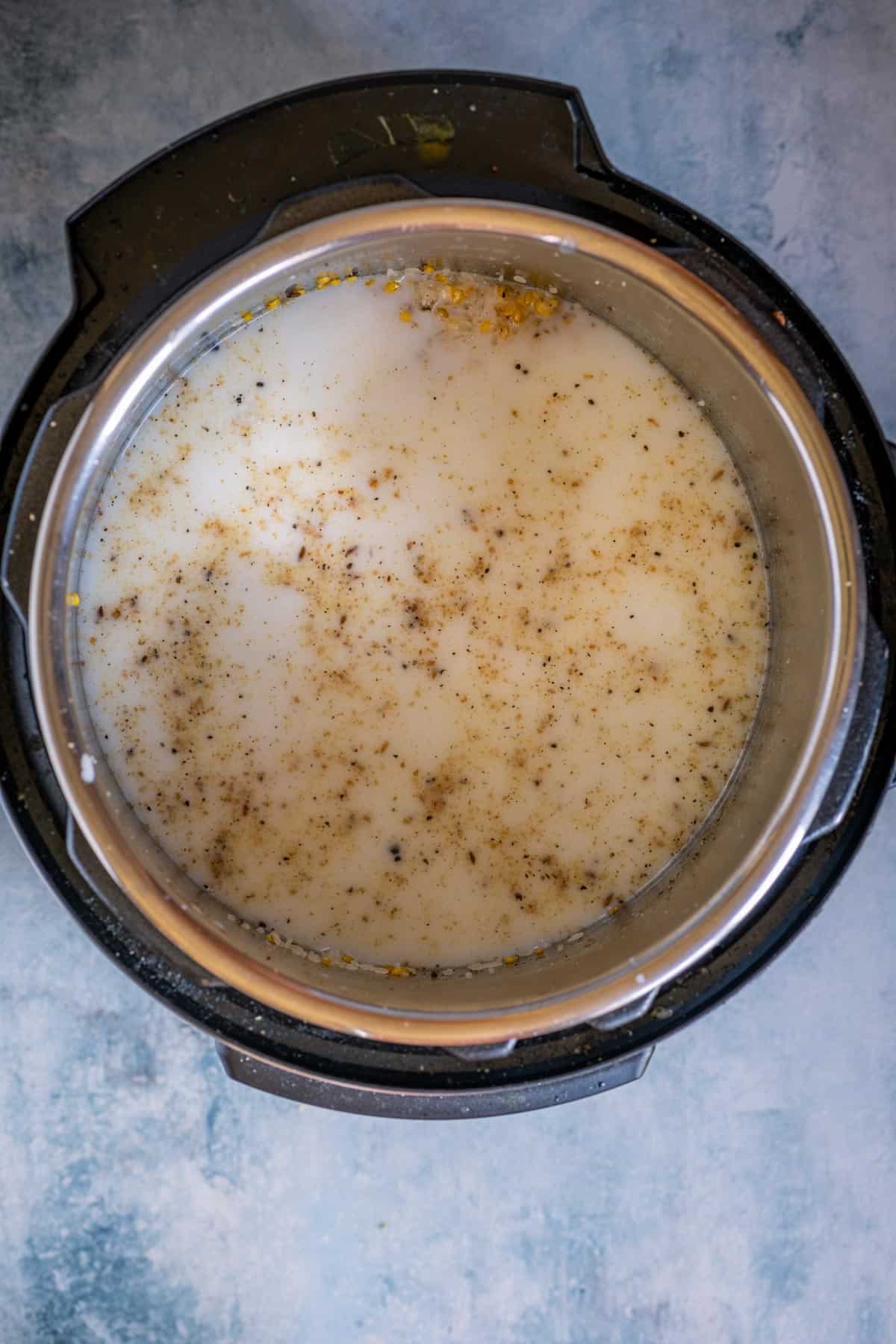 Instant Pot filled with rice, dal, milk, and spices ready to pressure cook for Ven Pongal.